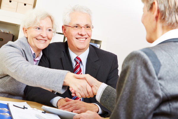 Happy elderly couple shaking hands with legal consultant in law