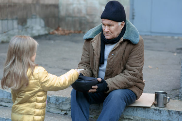 Little girl gives money to the beggar.