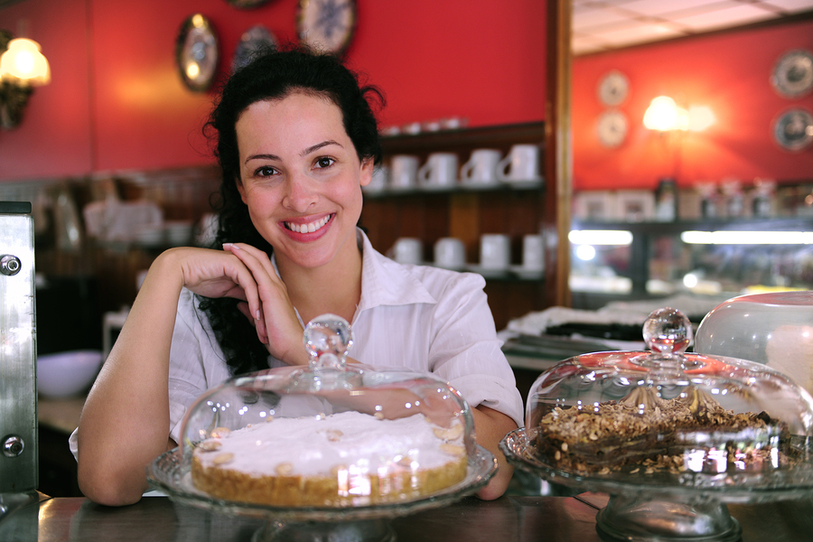 portrait of the owner of a small business/ cake store/ cafe/ coffee shop showing her tasty cakes